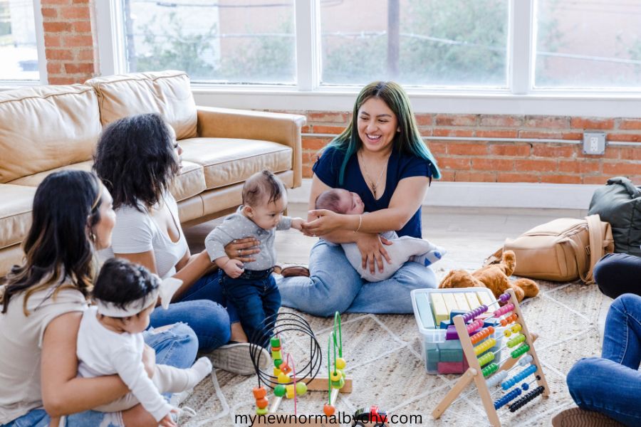 a-group-of-three-moms-all-sitting-on-the-floor-each-with-a-baby-smiling-and-talking-how-to-boost-your-confidence-as-a-new-mom