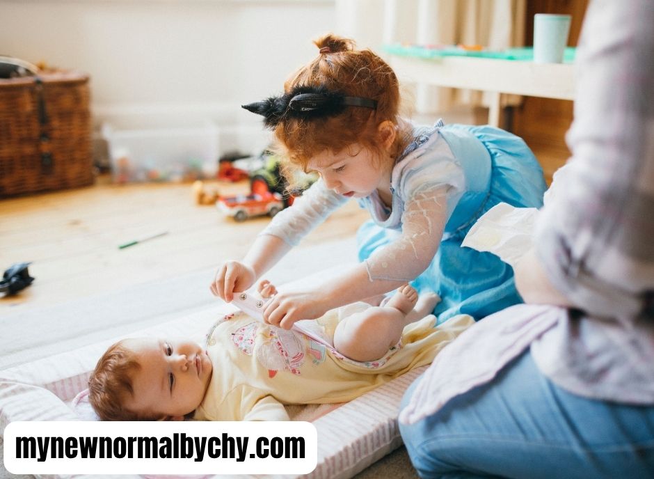 Toddler-girl-is-helping-her-mom-change-her-baby-sister's-diaper